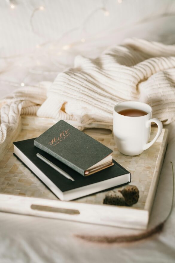 Journal next to cozy covers and a coffee mug for a quiet moment of reflection in which you can tune into what feels aligned for you.